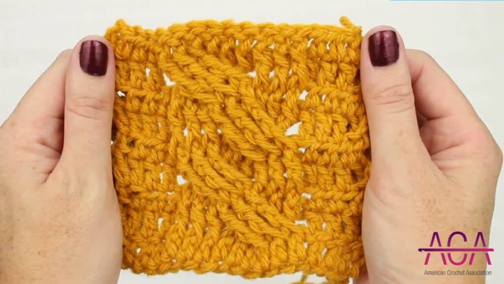 hands holding arabel cable stitch crochet swatch